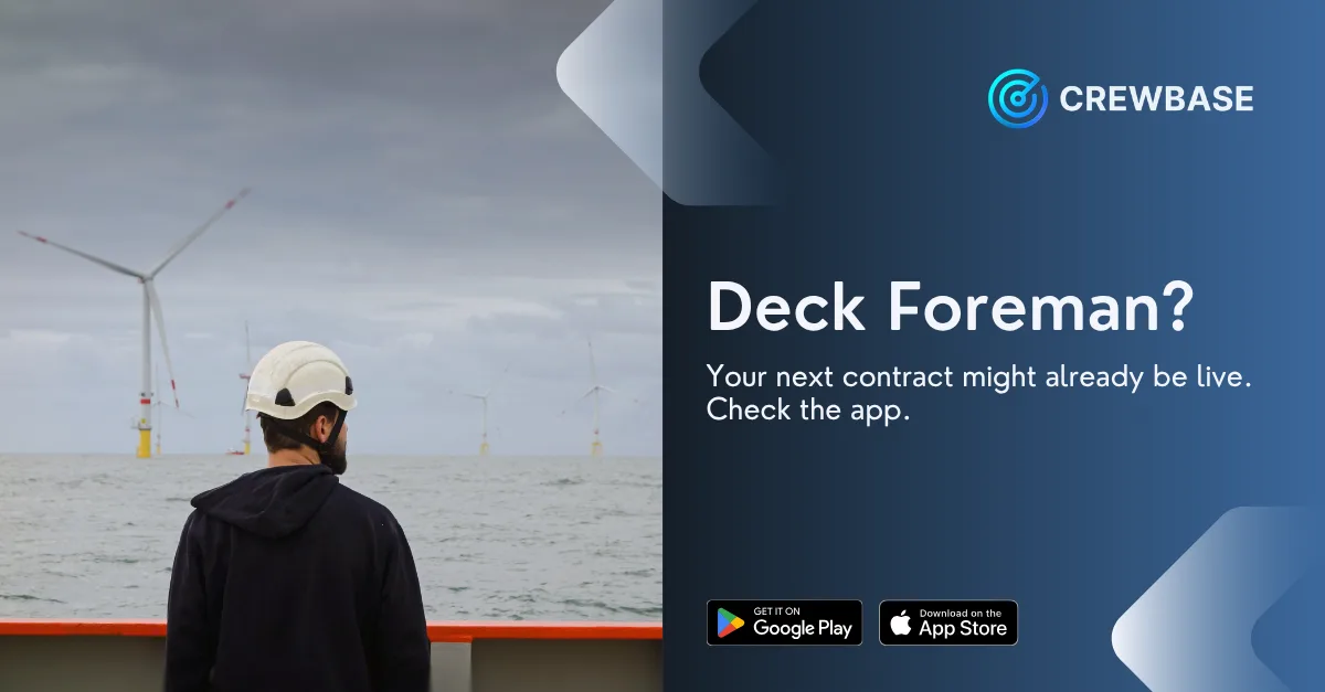 Deck foreman in hard hat viewing offshore wind turbines with CrewBase recruitment ad